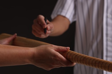 Photo of Baseball player signing autograph on bat against black background, closeup