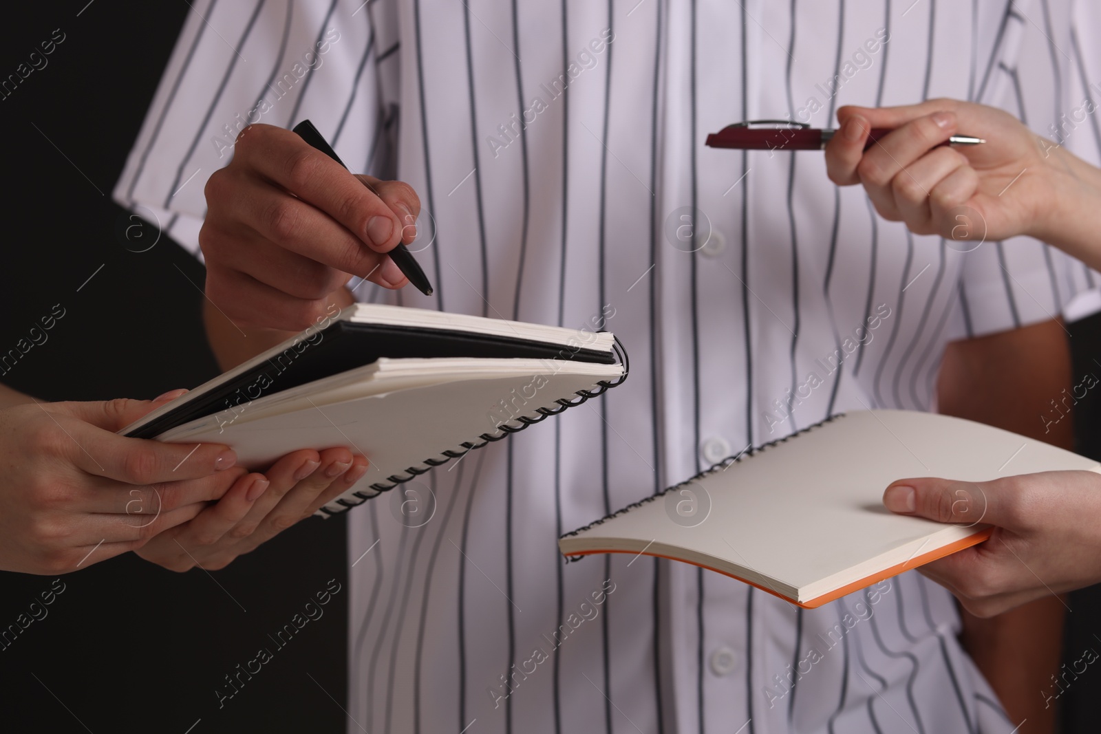 Photo of Baseball player signing autograph in notebook against black background, closeup