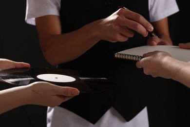 Photo of Singer signing autograph in notebook on black background, closeup