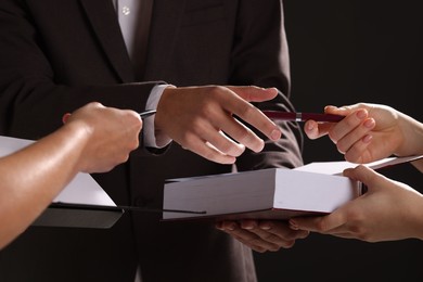 Photo of Writer signing autograph in book on black background, closeup