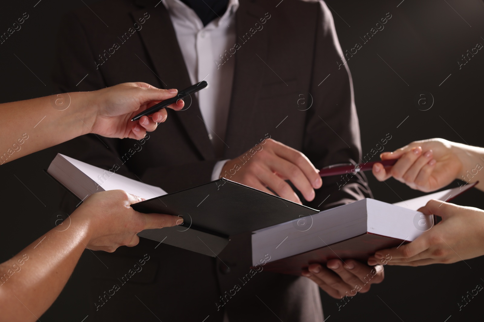 Photo of Writer signing autograph in book on black background, closeup