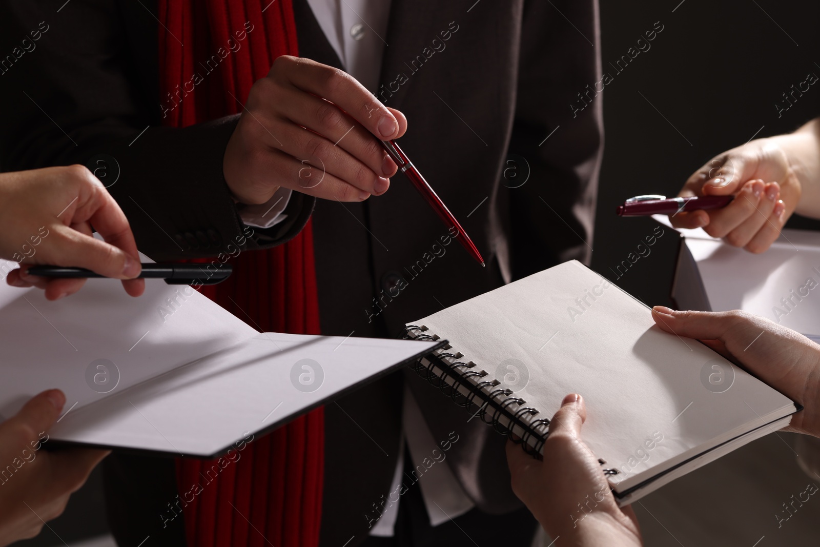 Photo of Man signing autograph in notebook on dark background, closeup