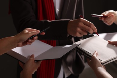 Photo of Man signing autograph in notebook on dark background, closeup