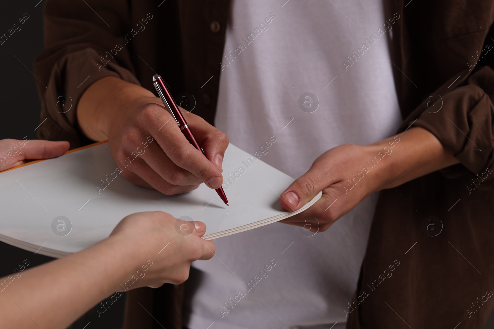 Photo of Man signing autograph in notebook, closeup view