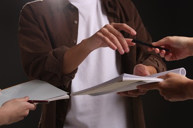 Photo of Man signing autograph in notebook on black background, closeup