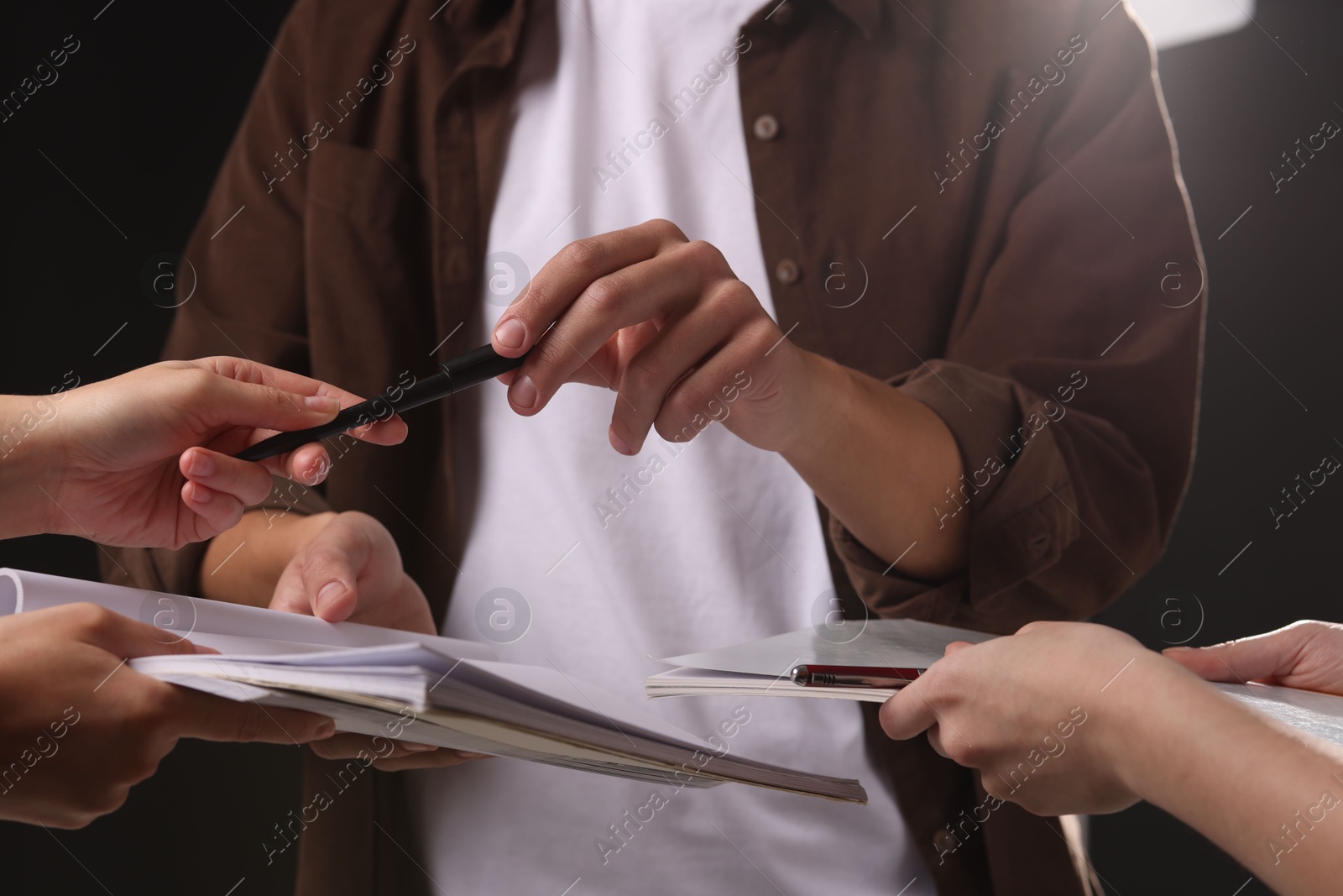 Photo of Man signing autograph in notebook on dark background, closeup