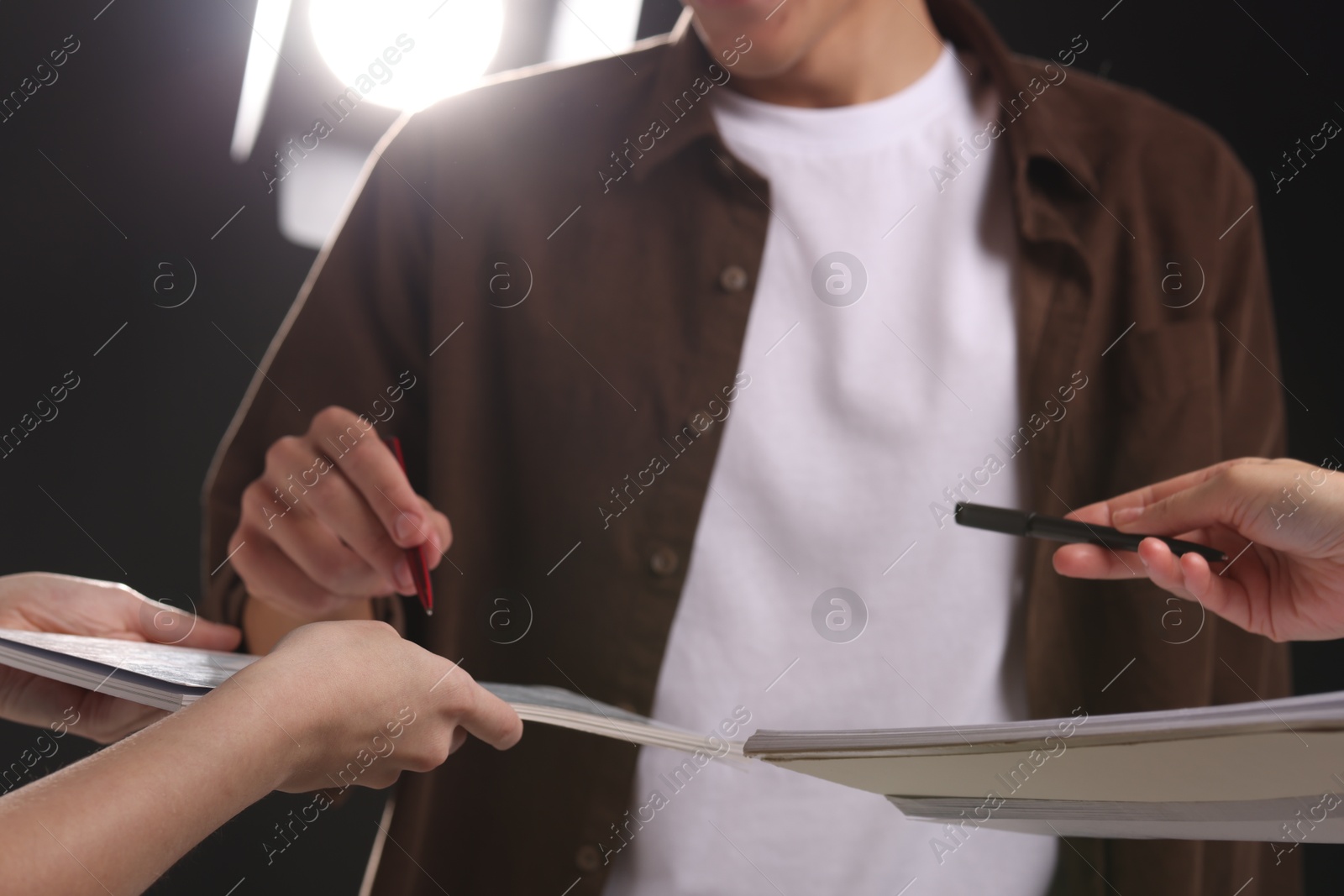 Photo of Man signing autograph in notebook on dark background, closeup