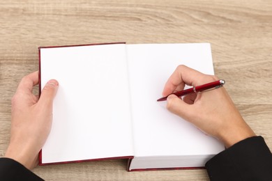 Photo of Writer signing autograph in book at wooden table indoors, above view