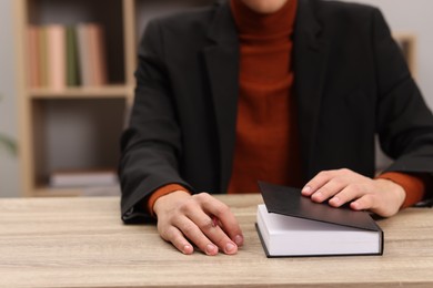 Photo of Signing autograph. Writer with pen and book at wooden table indoors, closeup