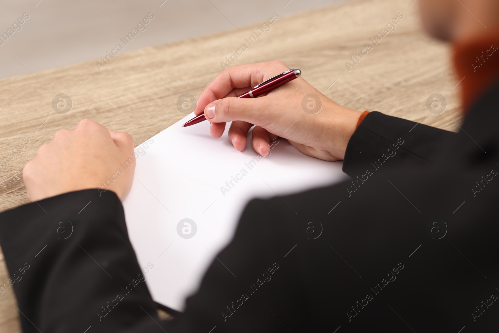 Photo of Writer signing autograph in book at wooden table indoors, closeup