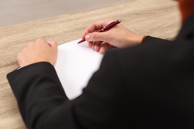 Photo of Writer signing autograph in book at wooden table indoors, closeup