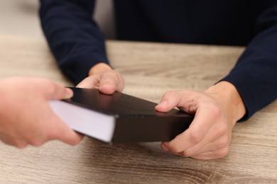 Photo of Writer signing book for reader at wooden table, closeup