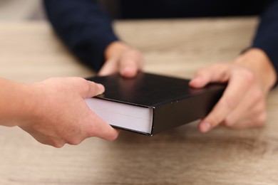 Photo of Writer signing book for reader at wooden table, closeup