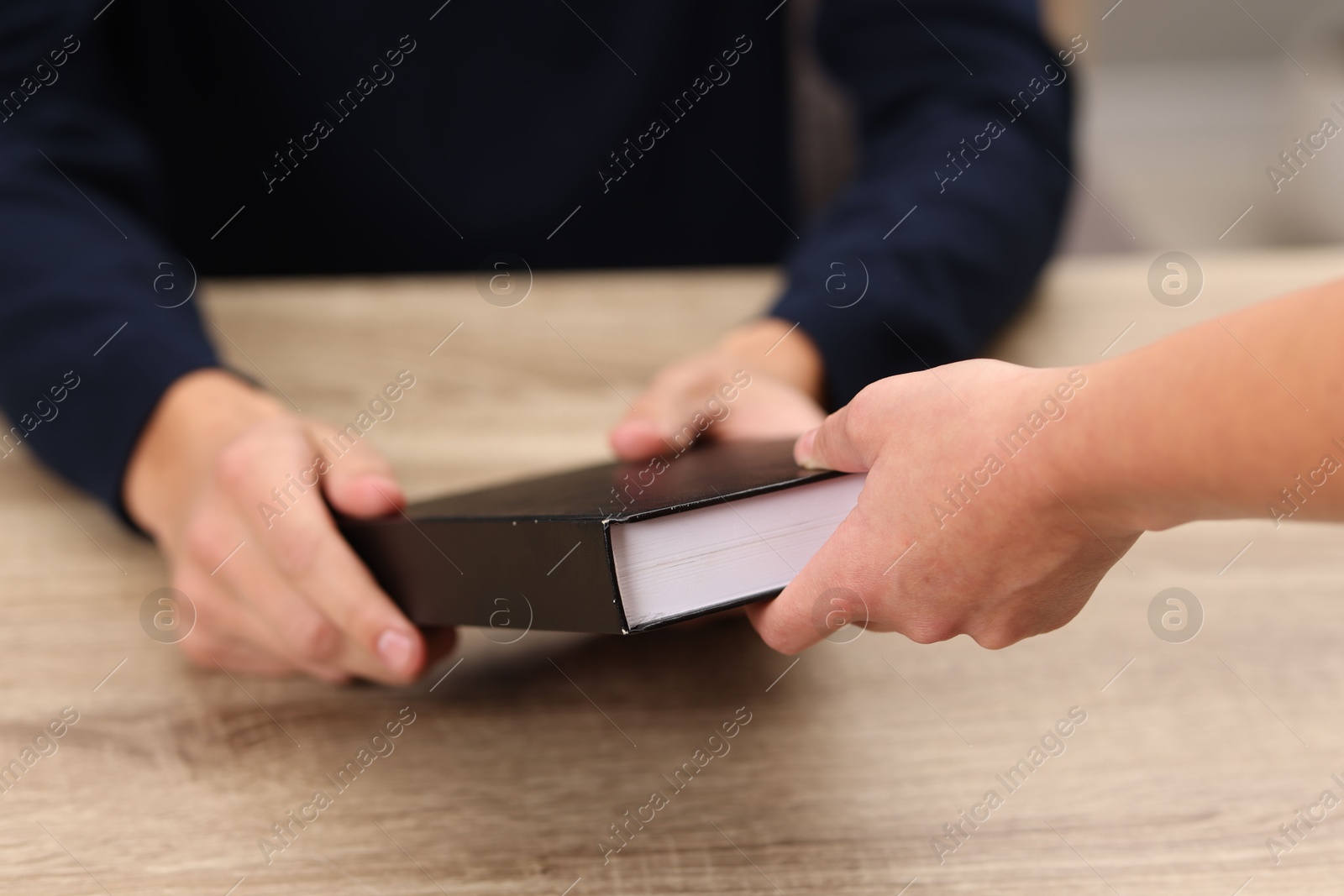 Photo of Writer signing book for reader at wooden table, closeup