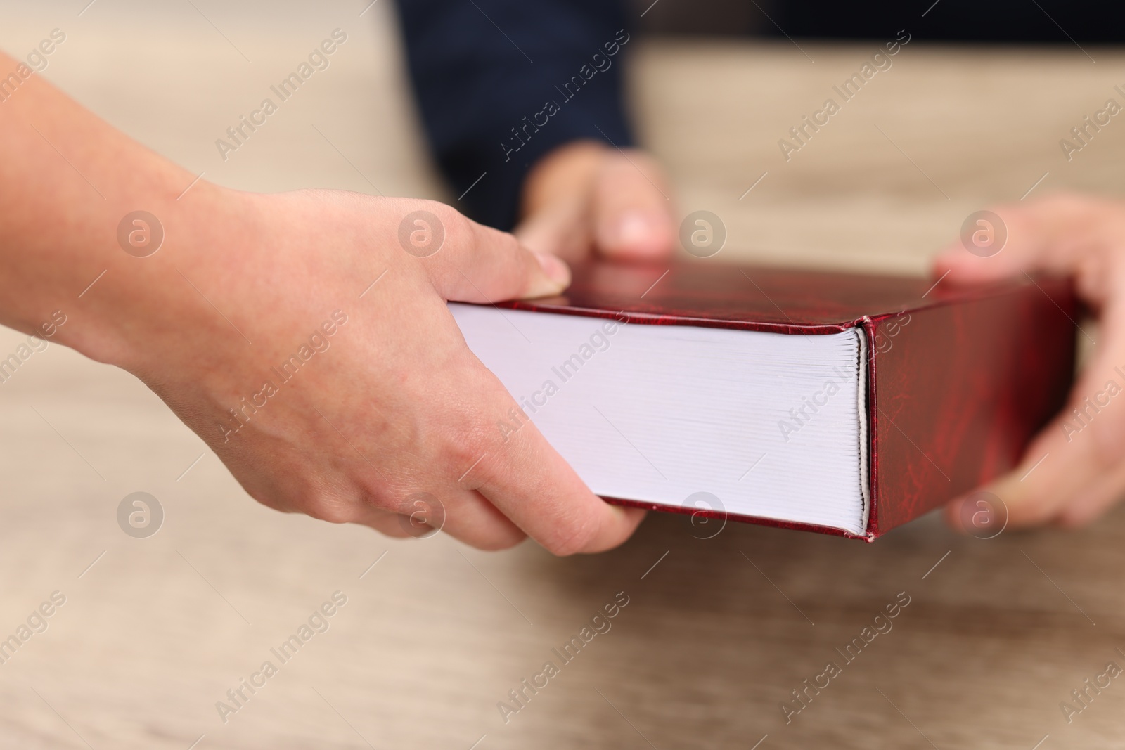 Photo of Writer signing book for reader at wooden table, closeup