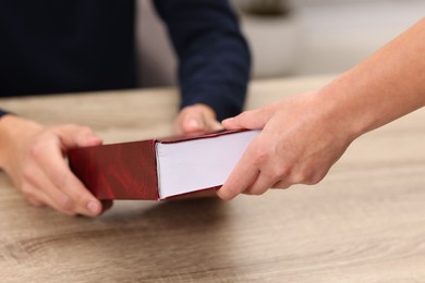 Photo of Writer signing book for reader at wooden table, closeup