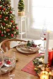 Photo of Christmas celebration. Festive table setting with dishware, glasses and decor in room