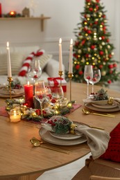 Photo of Christmas celebration. Festive table setting with dishware, glasses and decor in room