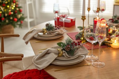 Photo of Christmas celebration. Festive table setting with dishware, glasses and decor in room