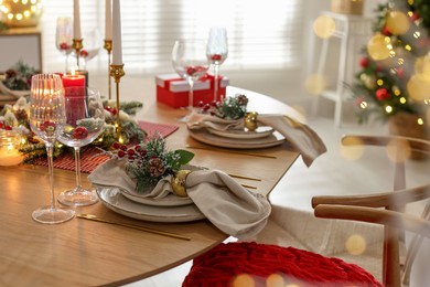 Photo of Christmas celebration. Festive table setting with dishware, glasses and decor in room