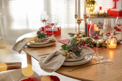 Photo of Christmas celebration. Festive table setting with dishware, glasses and decor in room