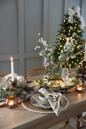 Photo of Christmas place setting with festive decor on wooden table in room