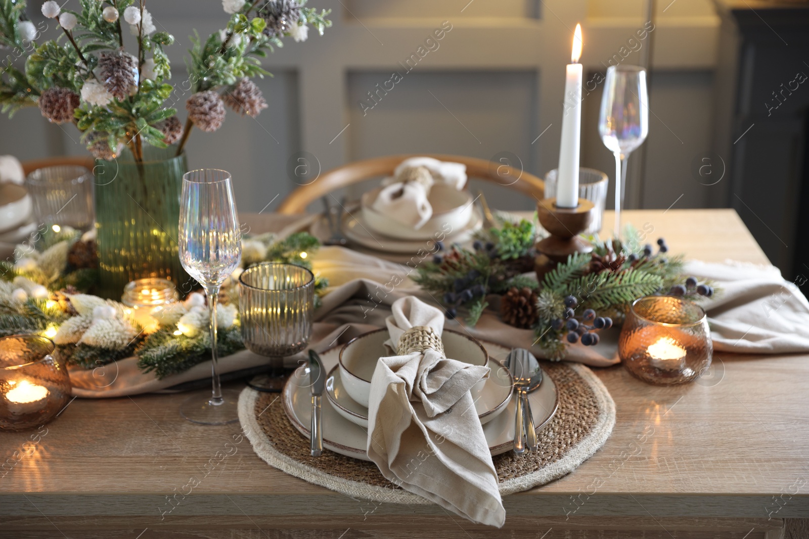 Photo of Christmas place setting with festive decor on wooden table in room