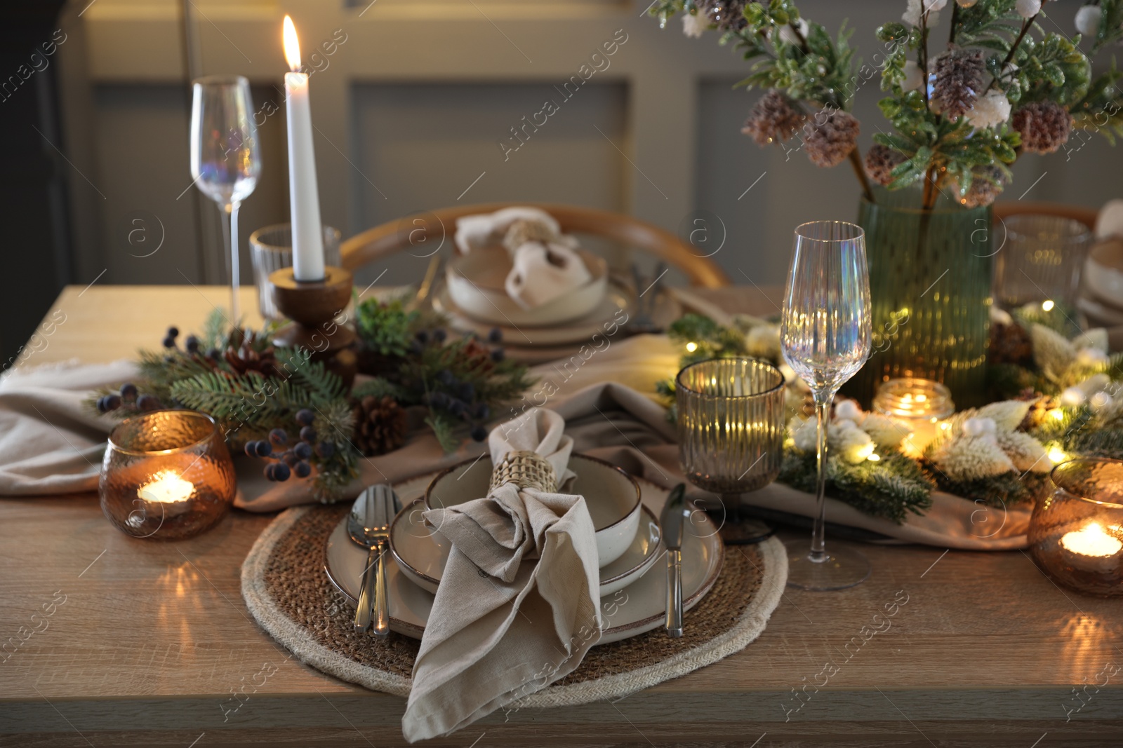 Photo of Christmas place setting with festive decor on wooden table in room