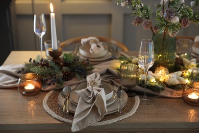 Photo of Christmas place setting with festive decor on wooden table in room