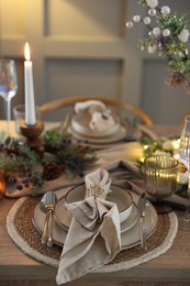 Photo of Christmas place setting with festive decor on wooden table in room