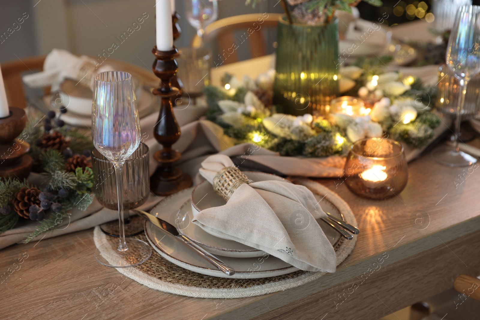 Photo of Christmas place setting with festive decor on wooden table in room, closeup