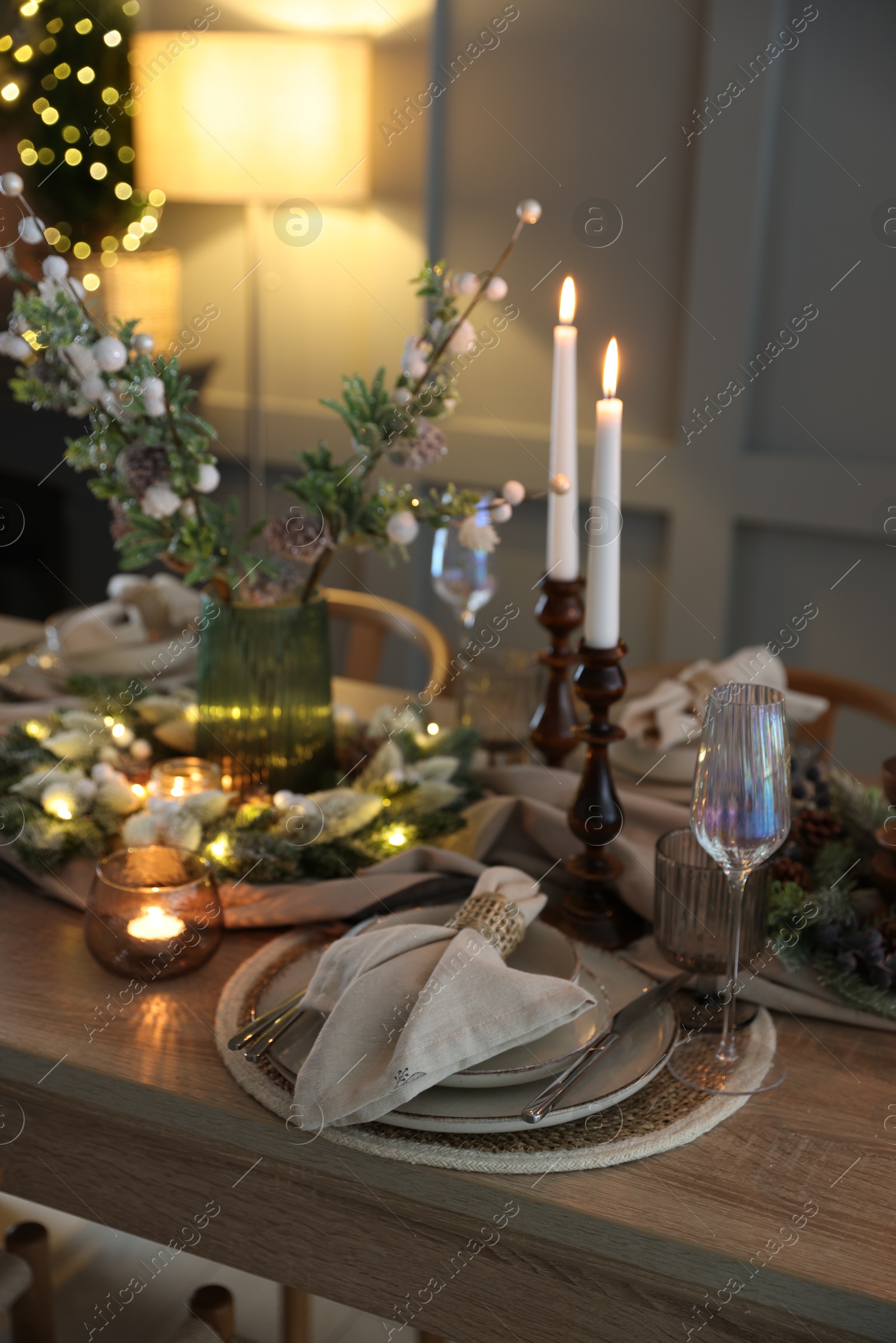 Photo of Christmas place setting with festive decor on wooden table in room