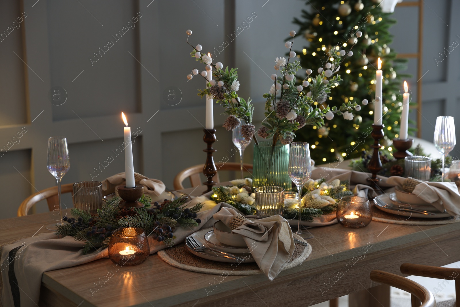 Photo of Christmas celebration. Festive table setting with dishware, glasses and decor in room