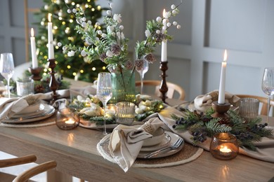 Photo of Christmas celebration. Festive table setting with dishware, glasses and decor in room