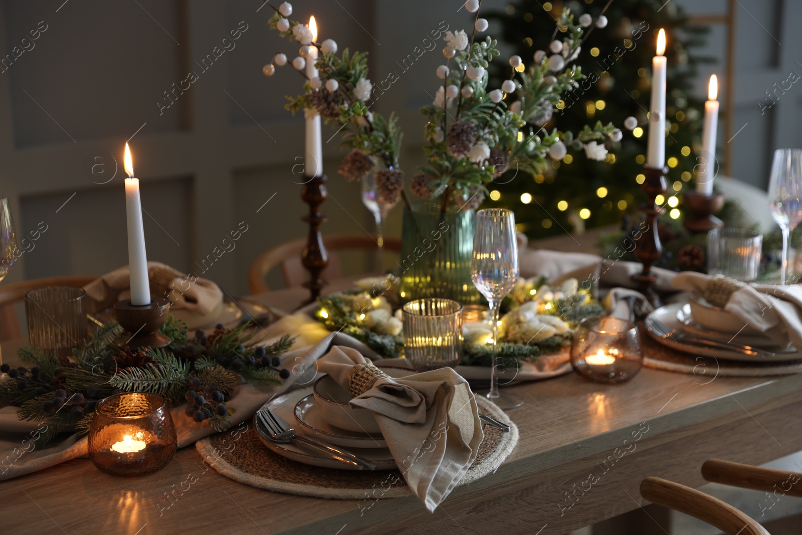 Photo of Christmas celebration. Festive table setting with dishware, glasses and decor in room