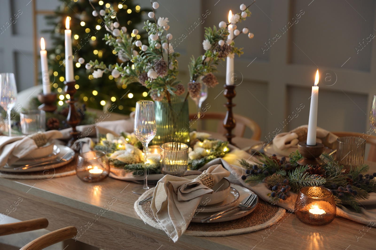 Photo of Christmas celebration. Festive table setting with dishware, glasses and decor in room