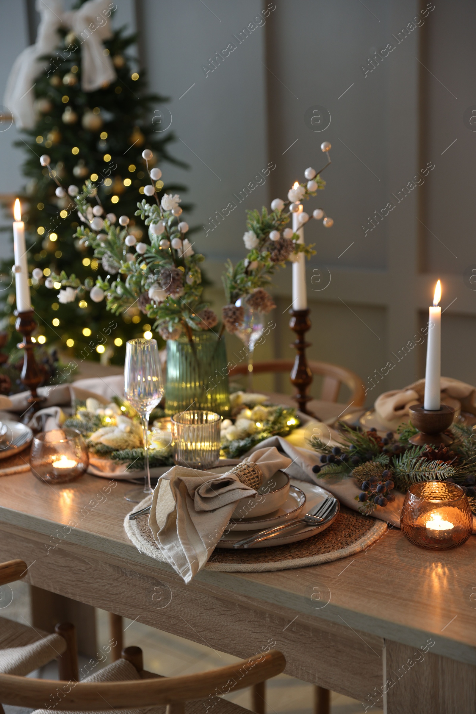 Photo of Christmas celebration. Festive table setting with dishware, glasses and decor in room