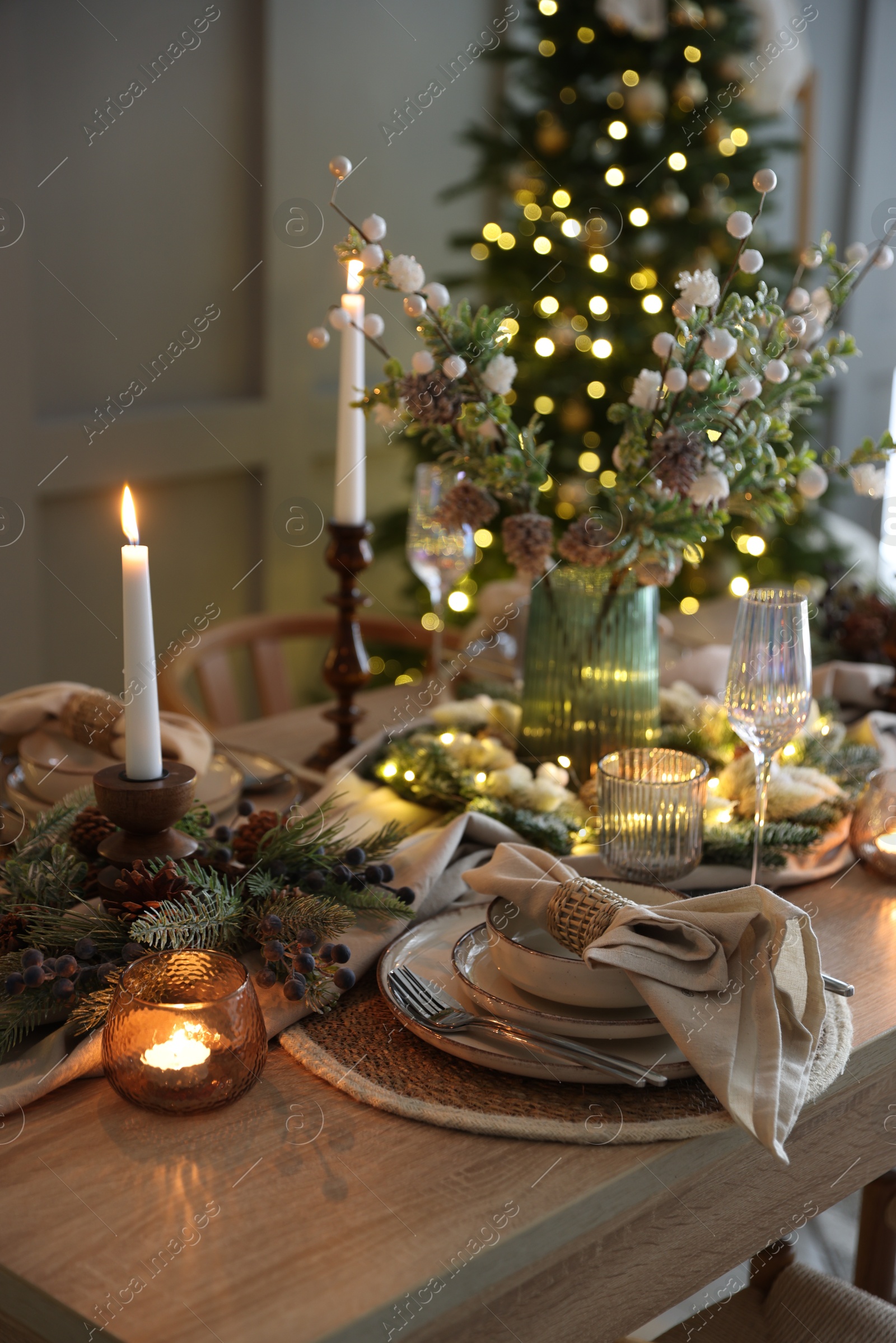 Photo of Christmas celebration. Festive table setting with dishware, glasses and decor in room