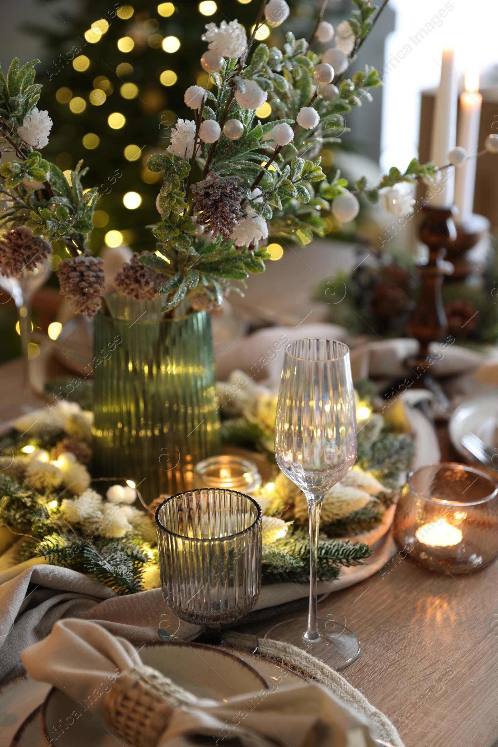 Photo of Christmas place setting with festive decor on wooden table in room