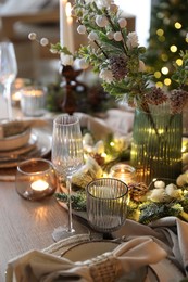 Photo of Christmas place setting with festive decor on wooden table in room