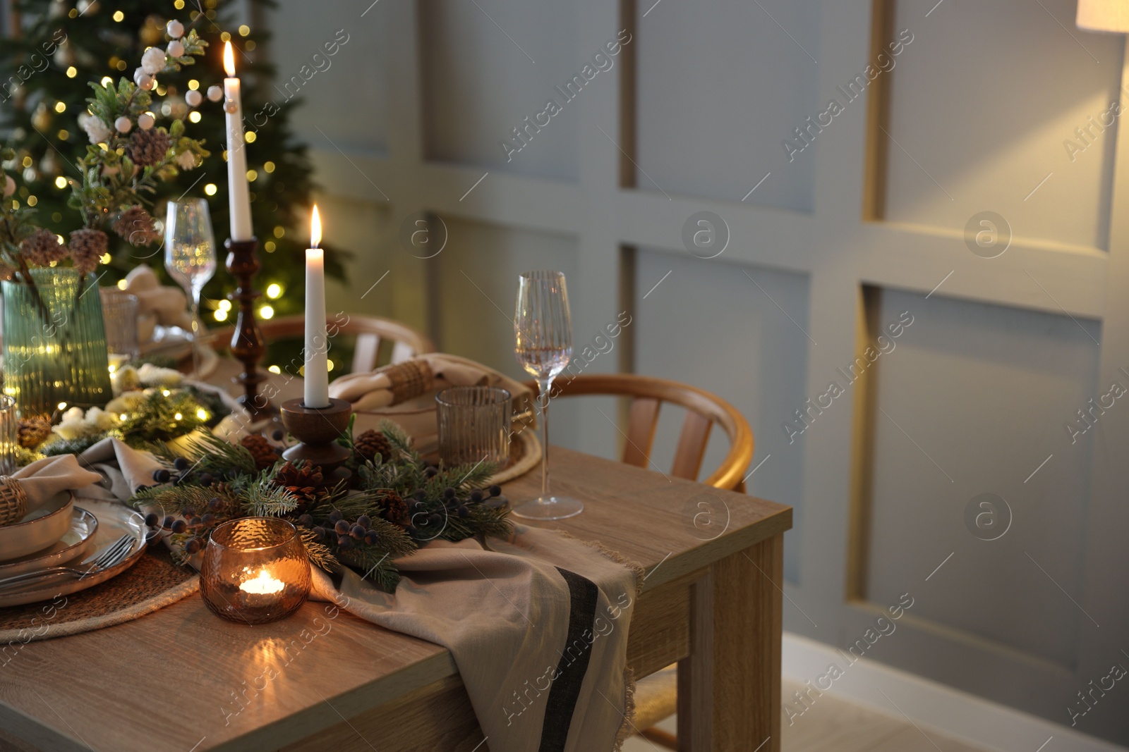 Photo of Christmas celebration. Festive table setting with dishware, glasses and decor in room