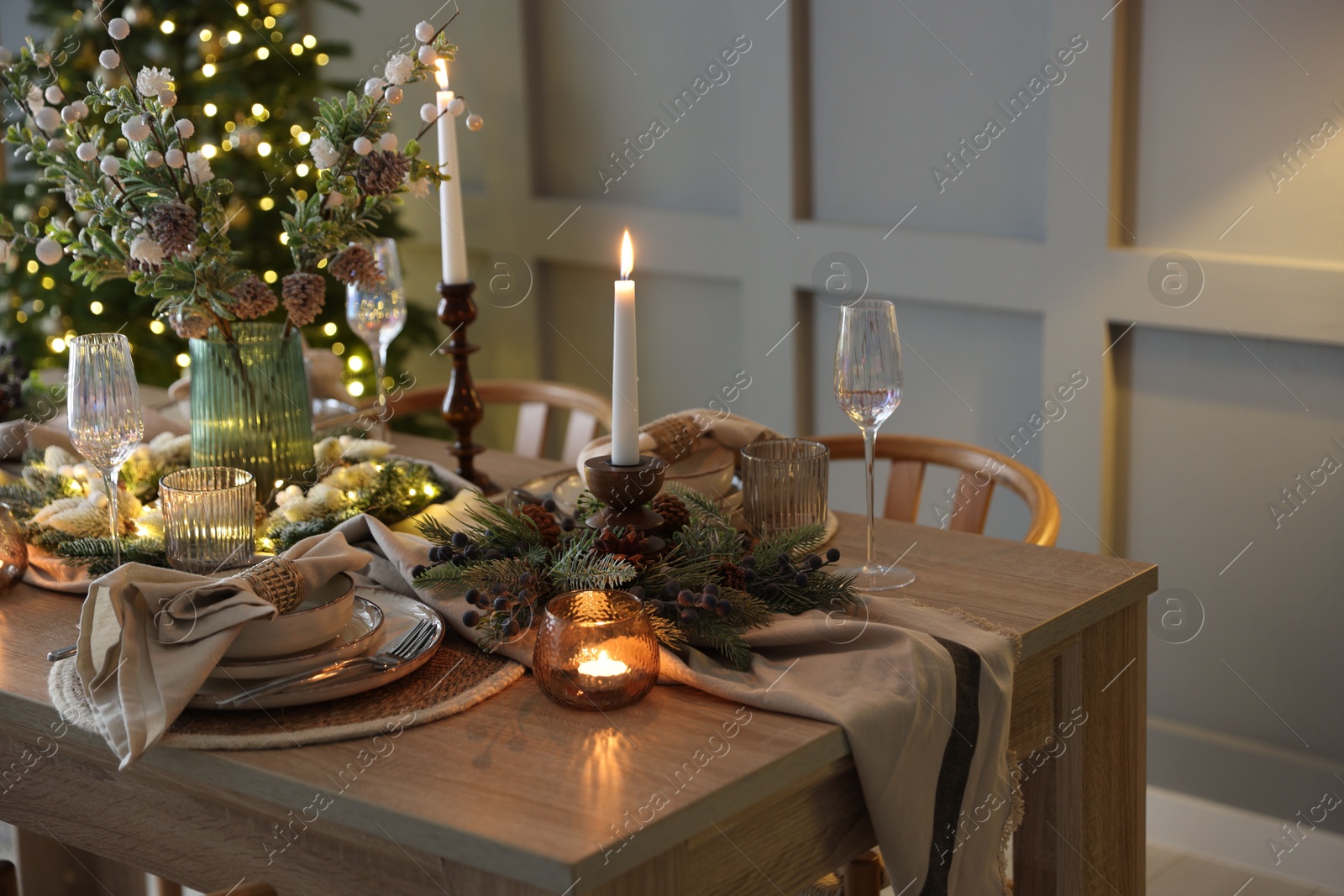 Photo of Christmas celebration. Festive table setting with dishware, glasses and decor in room