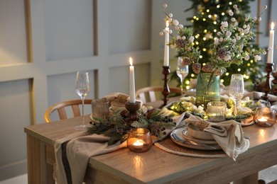 Photo of Christmas celebration. Festive table setting with dishware, glasses and decor in room