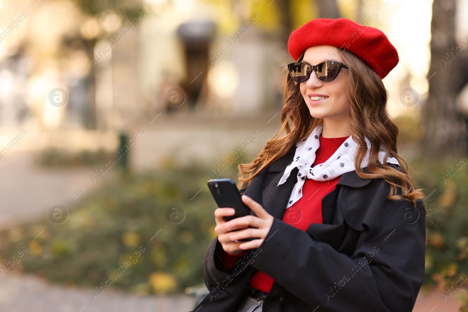 Photo of Stylish young woman with smartphone outdoors, space for text