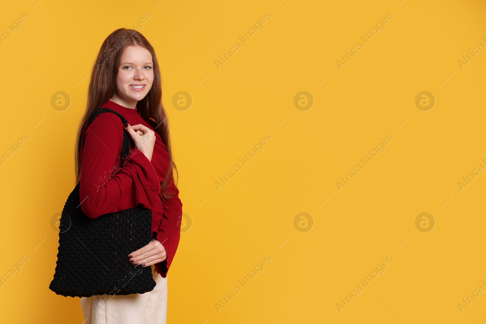 Photo of Teenage girl with handmade macrame bag on yellow background. Space for text