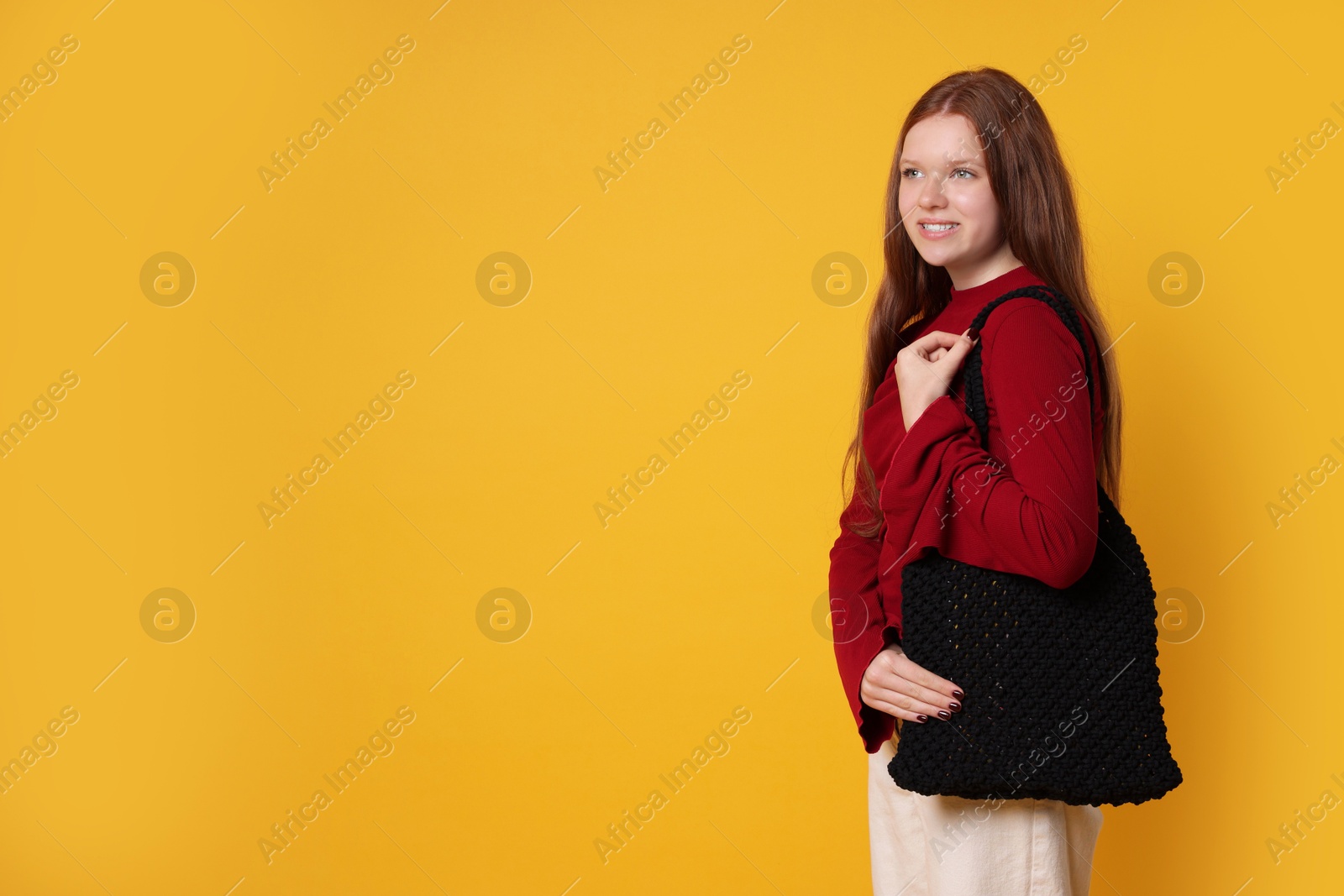 Photo of Teenage girl with handmade macrame bag on yellow background. Space for text