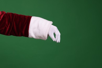 Photo of Santa Claus holding something on green background, closeup. Space for text