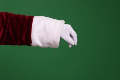 Photo of Santa Claus holding something on green background, closeup. Space for text