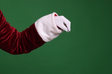 Photo of Santa Claus holding something on green background, closeup. Space for text