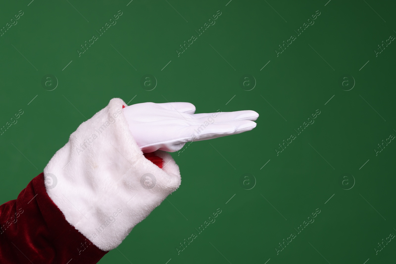 Photo of Santa Claus holding something on green background, closeup. Space for text